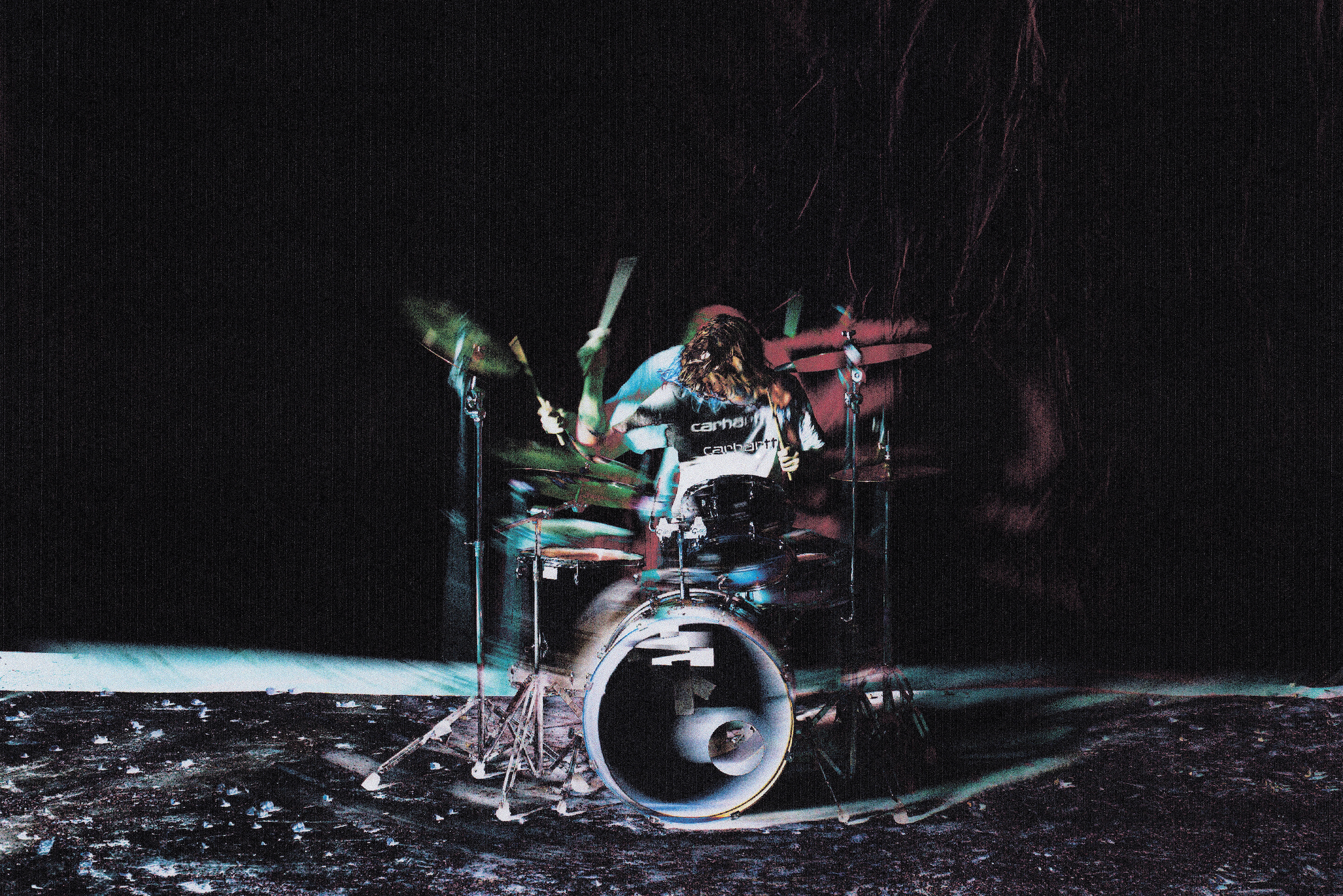 Carhartt WIP menswear styled on a drummer performing in a dark, moody setting